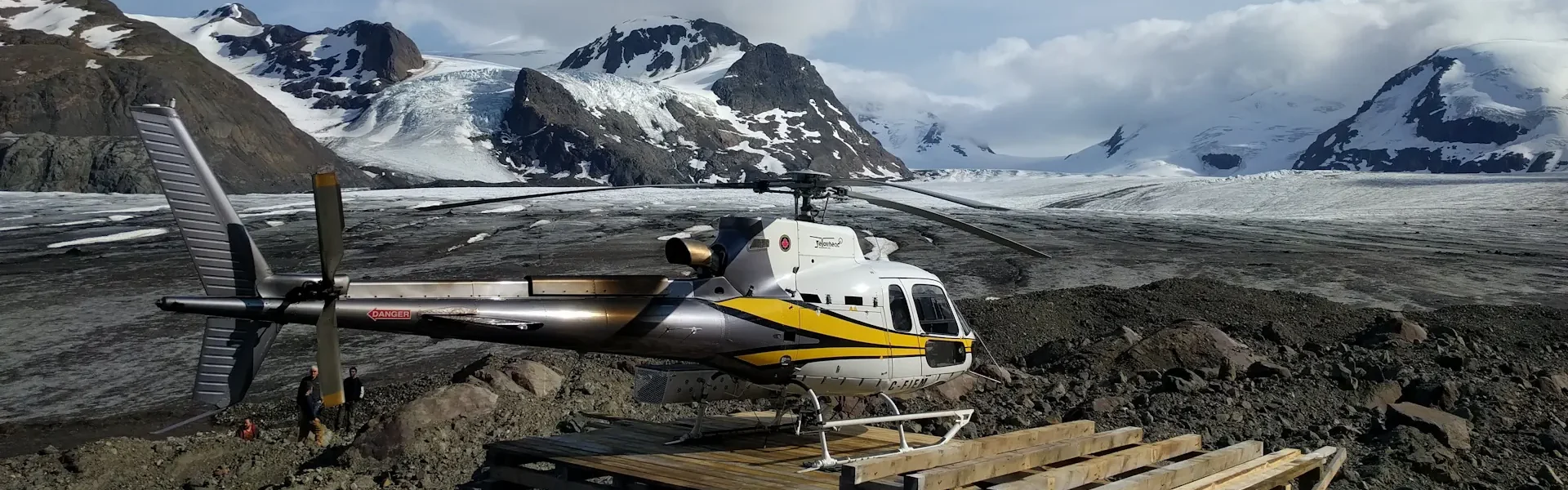 Photo of AS350B3 helicopter parked on a helipad in front of a glacier near Stewart BC
