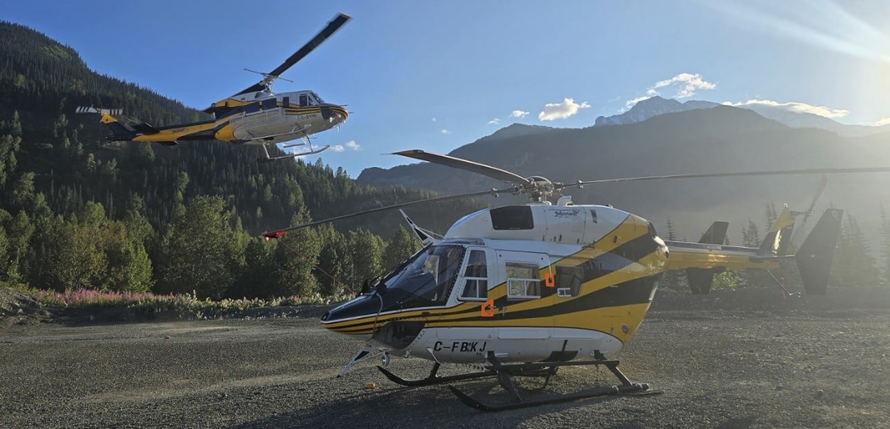 Bell212 helicopter flying in the background of a BK117 parked on the ground